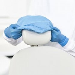 Cirujano dental con guantes y bata protectora preparando equipo odontológico en clínica dental moderna.